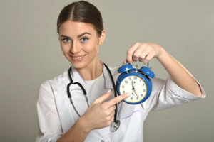 Physical therapist pointing at a clock indicating a physical therapist working hours